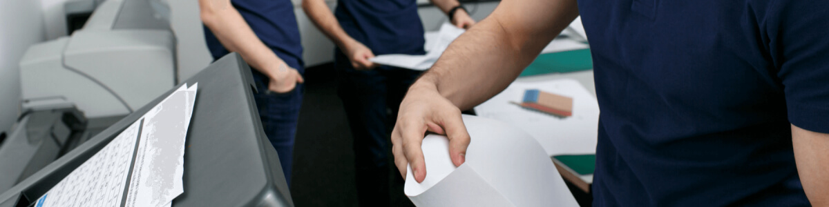 Close up of man putting in or taking out paper from a office scanner or copier tray