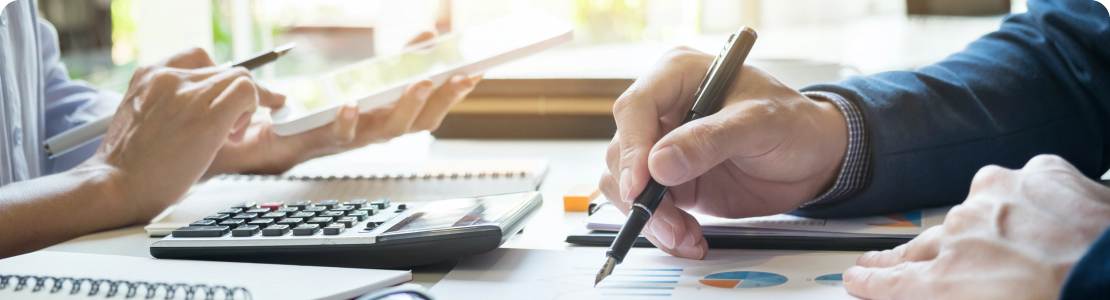 Hand with pen hovering over document on desk