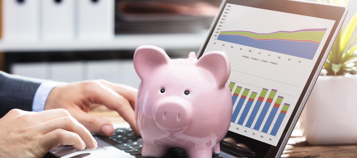 Businessperson Analyzing Graph On Laptop With Piggy Bank On Keypad